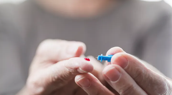 A diabetic tests her blood sugar. Close-up of the fingers of a senior woman with a drop of blood.
