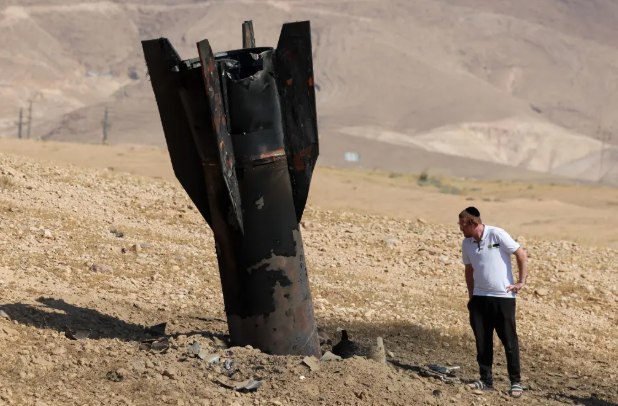 A man looks at a fallen rocket half-buried in Jericho on June 8, 2026
